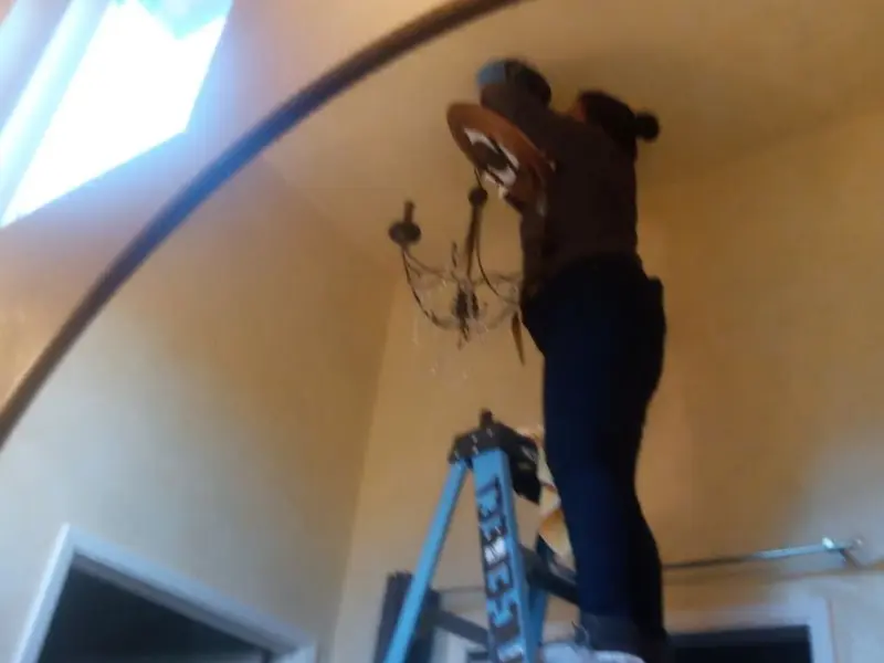Electrician installing a chandelier in a Holiday Shores residence
